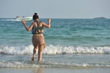 Güzel kız kumlu plaj manzarası ile tatlı bir gülümseme ve neşeli bir jest gönderiyor,