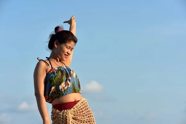 The beautiful girl is sending a sweet smile and a cheerful gesture with the view of the sandy beach,