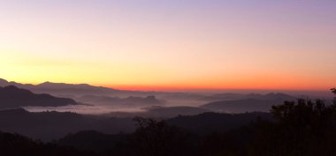 Gün batımında sisli dağ manzarası