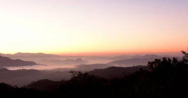 Gün batımında sisli dağ manzarası