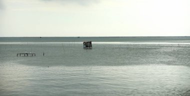 Bulutlu gökyüzü arka planında sakin suyu olan deniz manzarası 