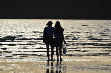 İnsanlar gün doğumunda deniz kıyısında dinleniyorlar.