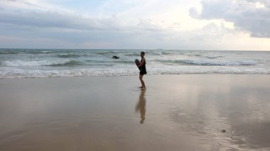 İnsanlar okyanus kıyısında gün batımının keyfini çıkarıyor.