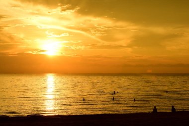 Sabahın erken saatlerinde denizin yanında sahilde yükselen güneş ve altın sarısı gökyüzü