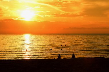 Sabahın erken saatlerinde denizin yanında sahilde yükselen güneş ve altın sarısı gökyüzü