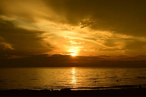 Sunrise at the beautiful beach view Among the many people come to play in the sea before the dusk.silhouette of sunrise at beach.