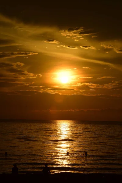 Sabahın erken saatlerinde denizin yanında sahilde yükselen güneş ve altın sarısı gökyüzü