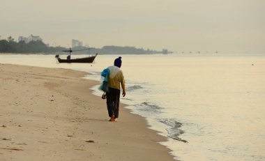 Genç adam sahilde koşuyor. 