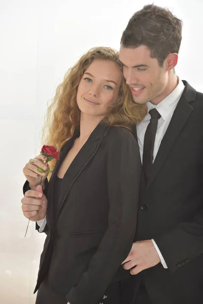 Businessman giving red flower to businesswoman, affair on workplace.