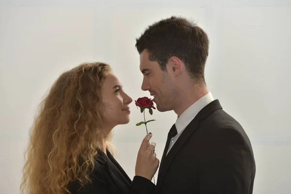 Businessman giving red flower to businesswoman, affair on workplace.
