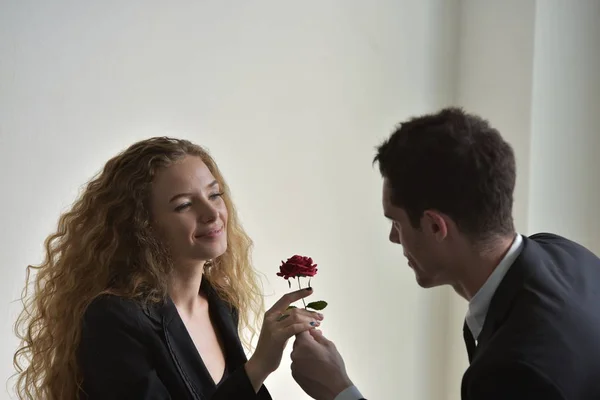 Businessman giving red flower to businesswoman, affair on workplace.