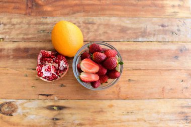 Portakal, nar ve dilimlenmiş çileği kaseye koy. 