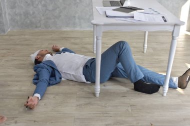 Bandajlı yaralı kafasıyla çok çalışan iş adamı dağınık belgelerle yerde yatıyordu.