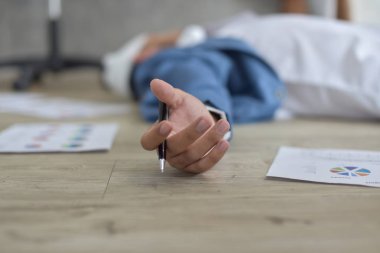 Bandajlı yaralı kafasıyla çok çalışan iş adamı dağınık belgelerle yerde yatıyordu.