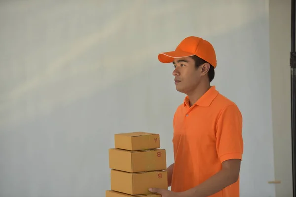 Young asian worker in orange delivery service uniform holding packages