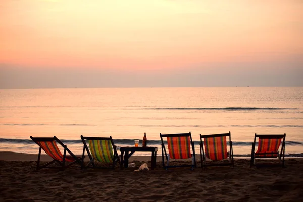 Sunset at seaside with lounge chairs.