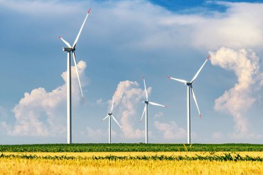 Yaz aylarında mavi gökyüzü ve beyaz bulutlar ile tarım alanında güneşli bir günde kırsal rüzgar enerjisi türbinleri