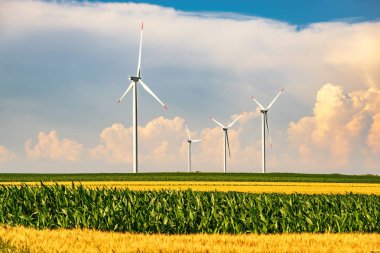 Yaz aylarında mavi gökyüzü ve beyaz bulutlar ile tarım alanında güneşli bir günde kırsal rüzgar enerjisi türbinleri