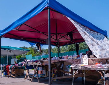 Kyiv, Ukrayna 3 d. Haziran 2025, Vibrant, Kyiv 'deki bir şehir pazarında, parlak bir tepe örtüsüyle kaplanmış, giysi ve ev eşyalarıyla dolu, yerel açık hava alışverişinin enerjisini gözler önüne seriyor.