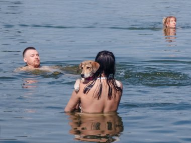 Kyiv, Ukraine 17th August,2025, People swimming in river with dog during summer day in Kyiv, Ukraine, showing relaxation, leisure, companionship, and everyday city lifestyle outdoors
