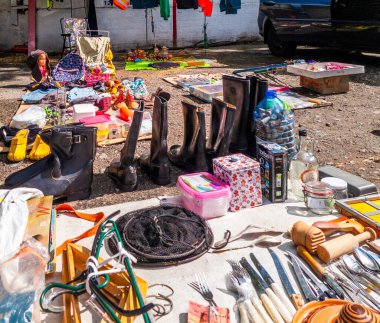 Kyiv, Ukraine 11th May,2025, Vibrant flea market scene with diverse secondhand goods including boots, utensils, clothing, tools, bottles, and toys displayed outdoors under bright sunlight