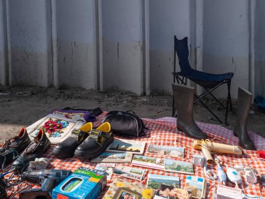 Kyiv, Ukraine 10th May,2025, Outdoor flea market in Kyiv showcasing secondhand goods including shoes, boots, books, tools, old magazines, and miscellaneous objects laid out on a patterned cloth
