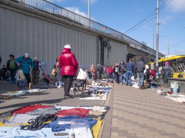 Kyiv, Ukraine 10th May,2025, Lively flea market in Kyiv city with people browsing used clothing and various goods displayed on the pavement under an overpass, reflecting urban street trade culture