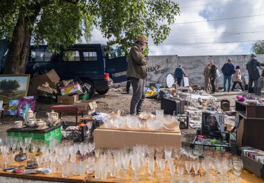 Kyiv, Ukraine 10th May,2025, Flea market in Kyiv with vendors selling vintage antiques, glassware, collectibles, and secondhand goods outdoors under trees on a bright sunny day