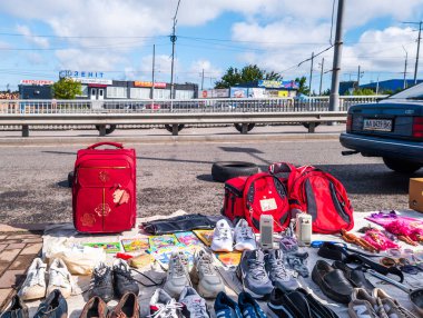 Kyiv, Ukraine 10th May,2025, Second hand street market in Ukraine showing shoes, red backpacks, books and small items laid out on the sidewalk near a roadside with urban buildings in background