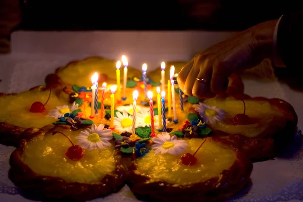 テーブルで暗闇の中の誕生日ケーキの女性手ライトろうそく — ストック写真