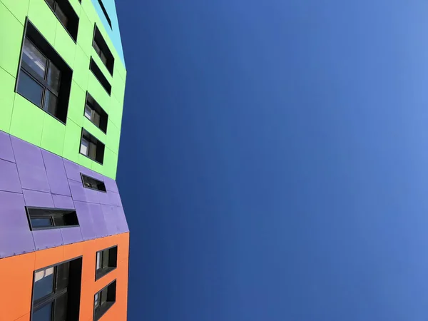 Okul siyah pencere çerçeveleri ile çok renkli parlak cephe. Mavi gökyüzüne bakmak yukarıya