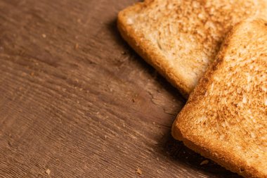 Lezzetli kızarmış ekmek dilimleri doğal kahverengi ahşap arka planda yatar. Basit kırsal biçim.