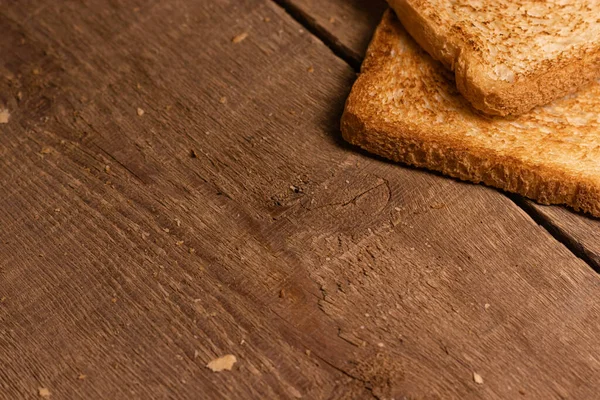 Lezzetli kızarmış ekmek dilimleri doğal kahverengi ahşap arka planda yatar. Basit kırsal biçim.