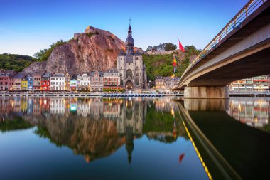 Dinant, Belgium. Cityscape image of beautiful historical city of Dinant with the reflection of the city in the Meuse River at summer sunset. clipart