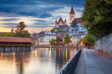 Thun, Switzerland. Cityscape image of beautiful city of Thun with the reflection of the city in the Aare river at sunset. clipart
