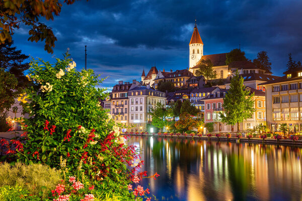 Thun, Switzerland. Cityscape image of beautiful city of Thun with the reflection of the city in the Aare river at night.