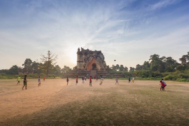 Mandalay, Myanmar - Şubat 18,2018: Birmanya kişi antik pagoda ile sahada futbol oynayan günbatımı, Inn Wa City, Mandalay, Myanmar sırasında arka planda Harabeleri