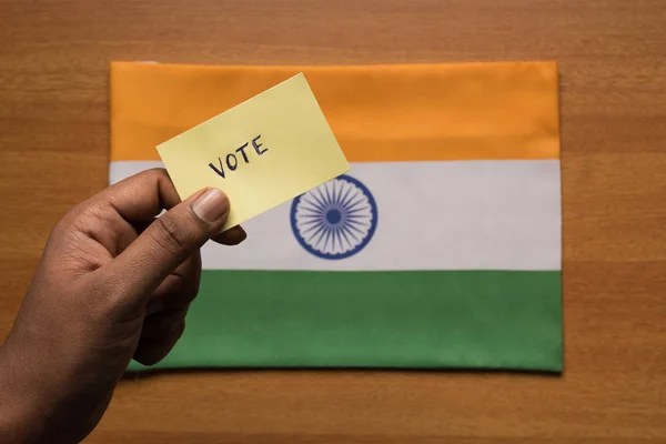 Voting concept - Person holding Hand Written Voting Sticker on India Flag. — Stock Photo, Image