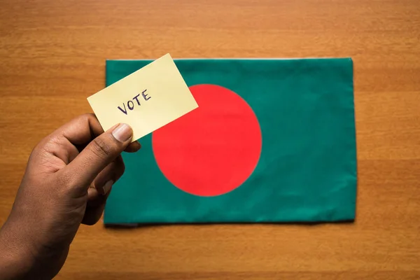 Concept de vote - Personne tenant un autocollant de vote écrit à la main sur le drapeau du Bangladesh . — Photo