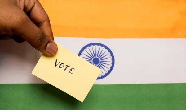 Концепція голосування - людина, яка тримає Руку, написану голосуванням, на індійському прапорі. — стокове фото