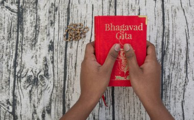 Maski, Karnataka, Hindistan - Aralık 29,2018: Holding Bhagavad Gita dokulu arka plan üzerinde elleriyle
