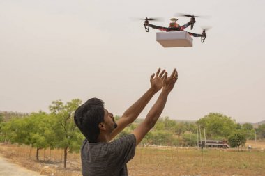 Drone teslimat kavramı, Uçan drone ürün alan genç adam