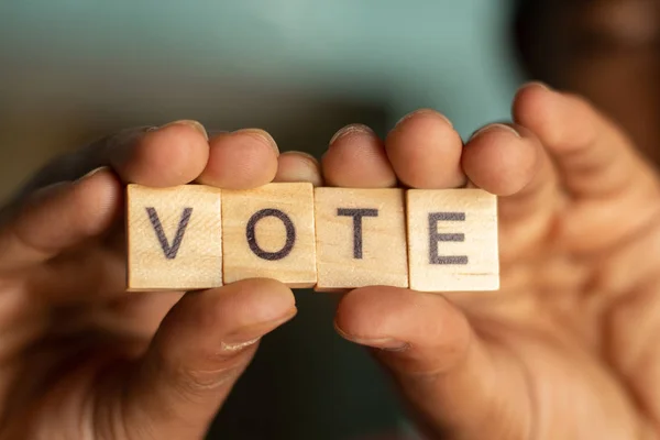 Hålla trä bloack brev visning av omröstning i händerna. — Stockfoto