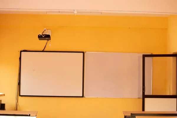 Aula con paredes amarillas y pizarras blancas con proyector . — Foto de Stock