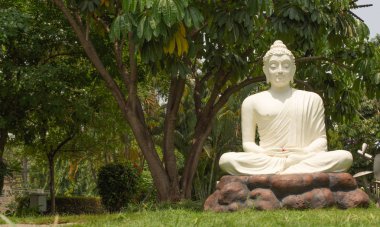 Bangalore, Karnataka Hindistan-04 Haziran 2019 : Beyaz Buda heykeli bir arka plan olarak doğa ile taş masa üzerinde meditasyon duruş