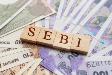 SEBI in wooden block letters on Indian Currency. clipart