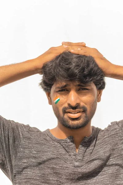 Portrait d'un jeune Indien curieux ou tendu fan de sport de cricket Drapeau indien peint sur son visage . — Photo