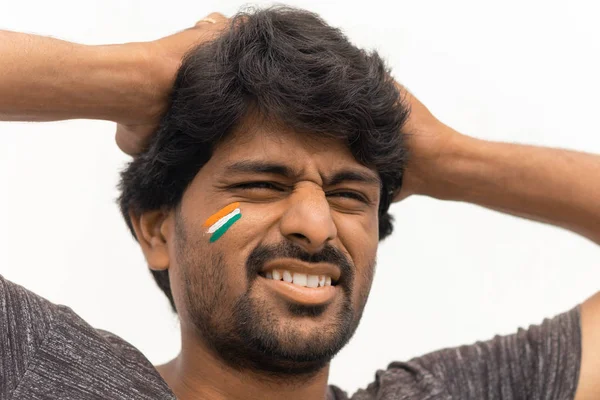 Closeup Shot, Sad expression of Male Indian Cricket sport fan with painted Indian flag on face, isolated background.