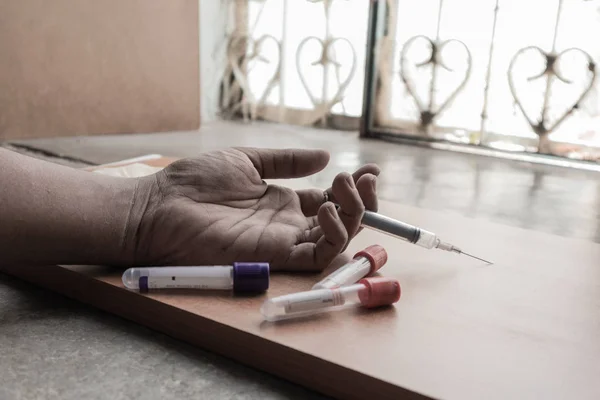 Drug Addict mână cu seringă pe podea cu tuburi de droguri . — Fotografie, imagine de stoc