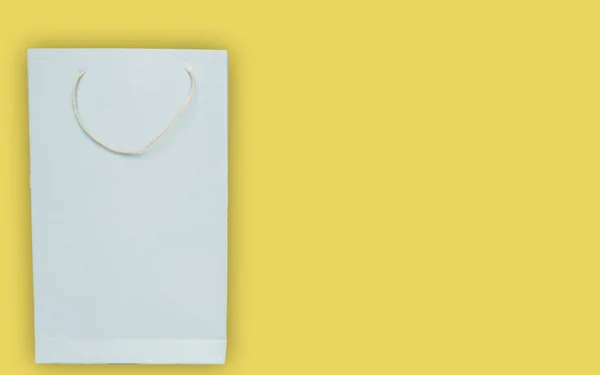 Ελαφρύ μπλε σακούλα χαρτιού για αγορές σε κίτρινο φόντο με χώρο αντιγραφής. — Φωτογραφία Αρχείου